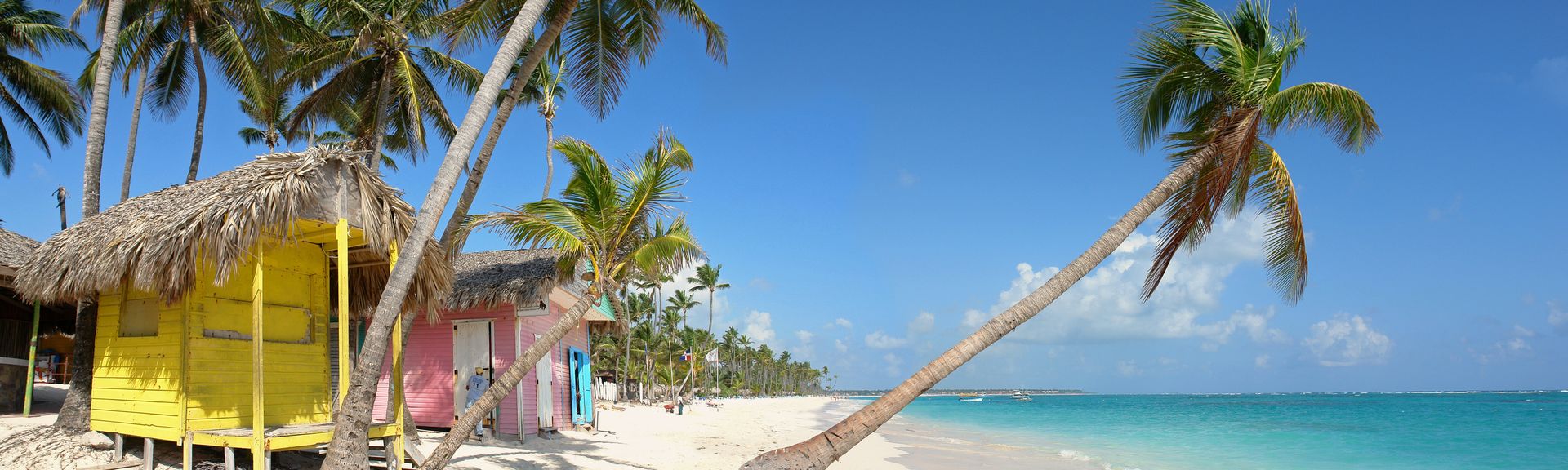 Urlaub in der Domrep: Ein weißer Strand mit Palmen und bunten Holzhäusern