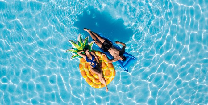 Romantik: Ein Paar liegt auf Luftmatratzen in einem Pool