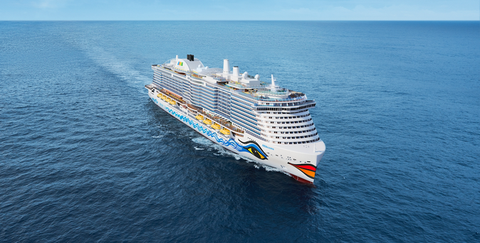 Ein riesiges, weißes Kreuzfahrtschiff der Reederei AIDA gleitet auf tiefblauem Meer dahin.