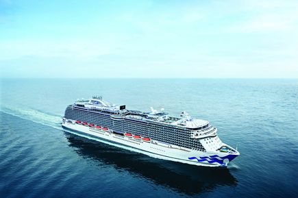 Ein riesiges, weiß-blaues Kreuzfahrtschiff der Reederei Princess Cruises gleitet auf dem tiefblauen Meer entlang.