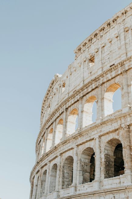 Italien Urlaub: Ein Ausschnitt des römischen Kollosseums unter blauem Himmel
