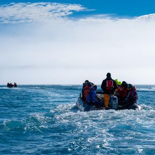 Oceanwide Expeditions: Ein Zodiac Boot fährt auf dem offenen Meer in Richtung eines Felsens
