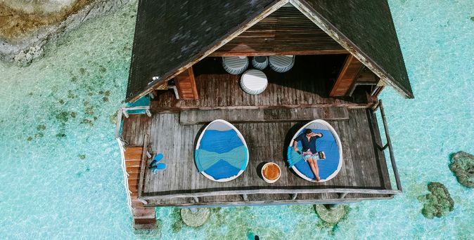Adults only Urlaub: Eine Luftaufnahme eines Holzbungalows auf türkisem, glasklaren Wasser