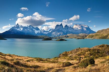 Eine Berglandschaft vor einem hellblauen See mitten in einer Steppenlandschaft.