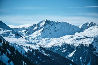 Winterurlaub Österreich: Hohe, verschneite Berge unter blauem Himmel