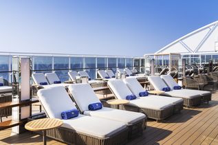 Auf dem Deck stehen viele weiße Sonnenligen mit blauen gebrandeten "MSC Yacht Club" Handtüchern