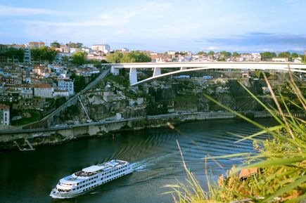 Kreuzfahrten: Ein weißes Flusskreuzfahrtschiff gleitet über einen Fluss durch eine Stadt