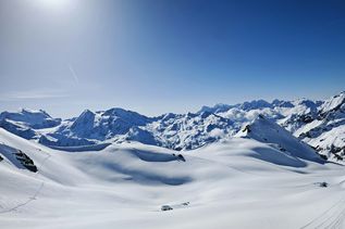 Winterurlaub Schweiz: Blauer Himmel und eine dicke Schneeschicht auf dem Berggipfel