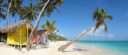Urlaub in der Domrep: Ein weißer Strand mit Palmen und bunten Holzhäusern
