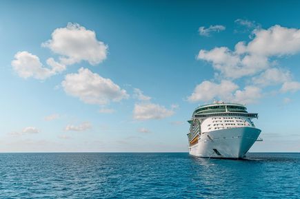 Kreuzfahrten: Ein riesiges, weißes Hochseekreuzfahrtschiff auf dem blauen Meer
