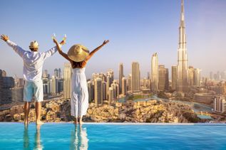 Ein Paar steht am Rand eines Infinity Pool und blickt auf die Skyline von Dubai