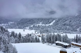 Winterurlaub Deutschland: Eine verschneite leicht hügelige Landschaft mit Holzhütten
