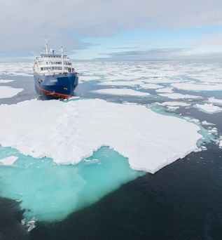 Oceanwide Expeditions: Ein Expeditionskreuzfahrtschiff fährt durchs Wasser und drumherum Eisschollen