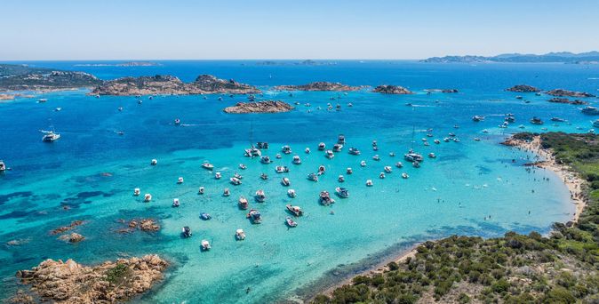 Strandurlaub: Ein türkis-blaues Meer mit vielen weißen Booten in Sardinien