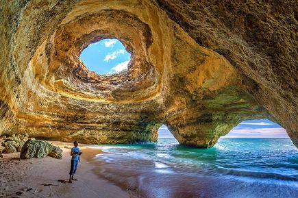 Urlaub in Portugal: Ein Mann steht unter einer skurrilen Felsformation an der portugiesischen Algarve