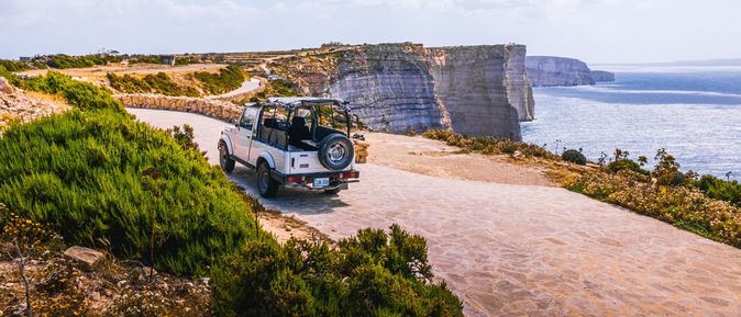 EIn Van fährt an einer Küstenstraße auf Gozo entlang.