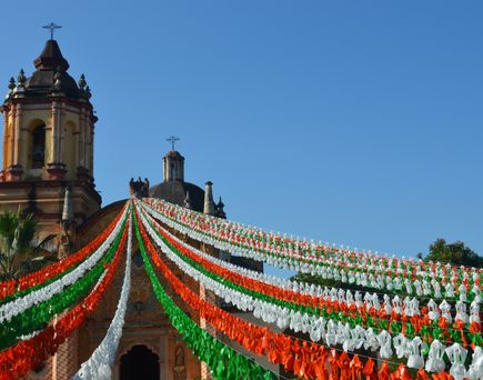 Mexiko im März: Eine Kirche an der in weiß-grün-rot Girlanden befestigt sind.