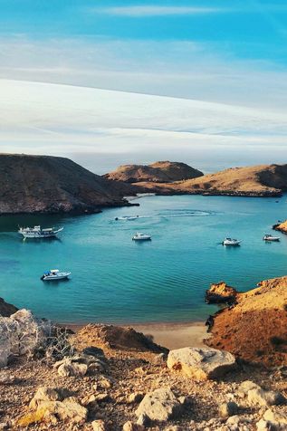 Urlaub im Orient: Eine felsige Landschaft am Meer mit einigen Booten