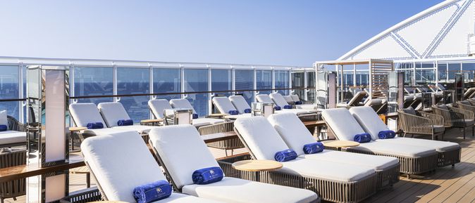 Kreuzfahrten 2026: Auf dem Deck eines MSC Kreuzfahrtschifss stehen weiße Sonnenliegen mit "MSC Yacht Club" Handtüchern