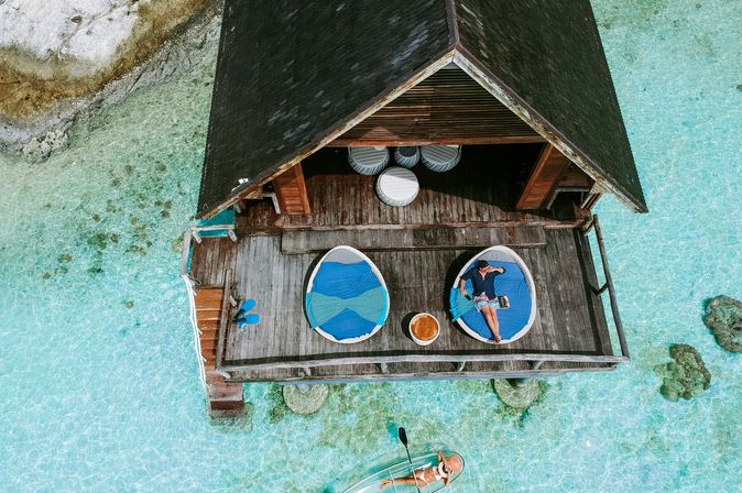 Adults only Urlaub: Eine Luftaufnahme eines Holzbungalows auf türkisem, glasklaren Wasser