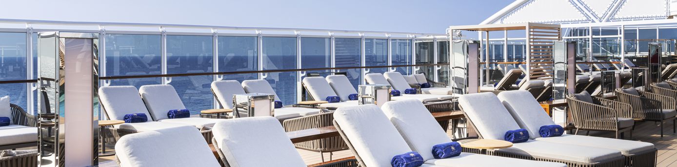 Kreuzfahrten 2026: Auf dem Deck eines MSC Kreuzfahrtschifss stehen weiße Sonnenliegen mit "MSC Yacht Club" Handtüchern