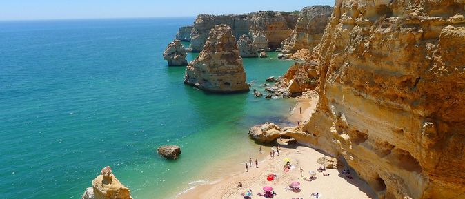 Ein belebter Strand mit vielen Felsen und Klippen an der portugiesischen Algarve