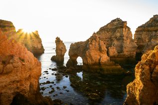 Frühbucher: Die untergehende Sonne strahlt skurrile Felsformationen im Wasser an