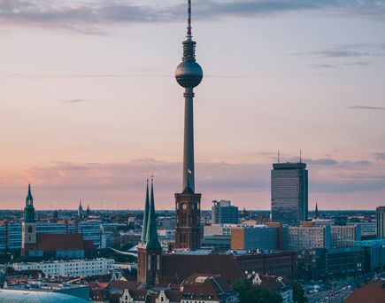 DE Urlaub: Blick auf den Berliner Fernsehturm, das rote Rathaus im Sonnenuntergangshimmel