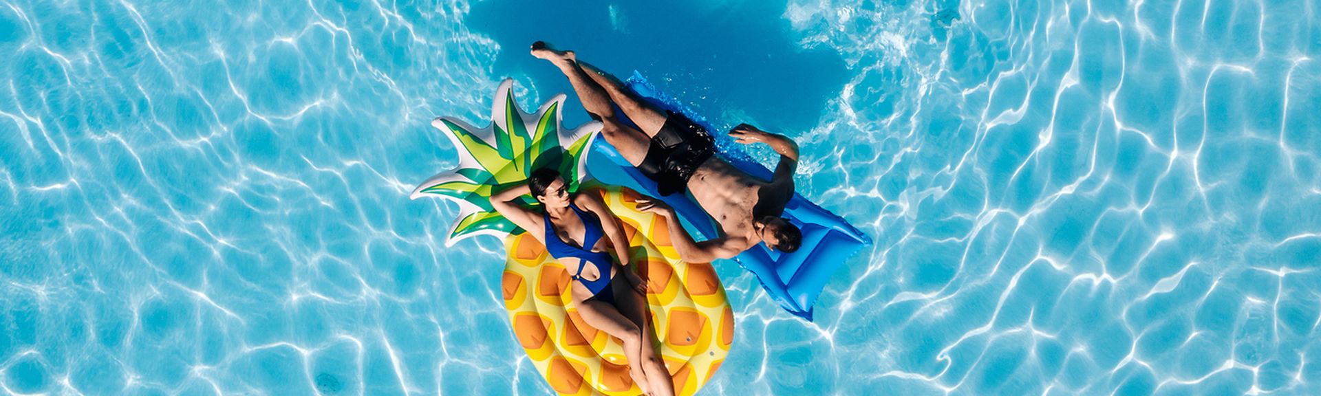 Resturlaub: Ein junges Paar liegt auf Luftmatratzen im Pool