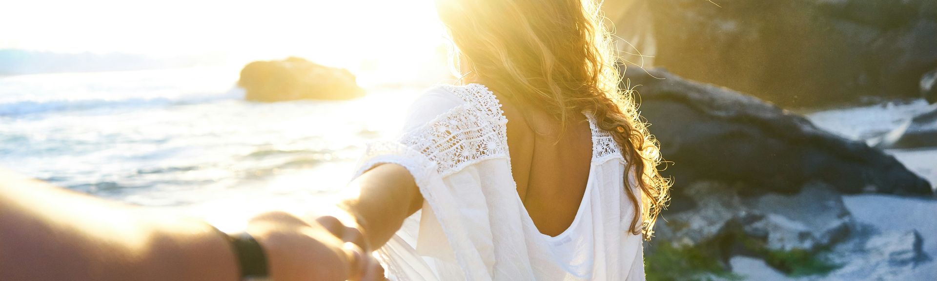 Adults only: Eine Frau hält einen Männerarm an der Hand und läuft auf einen Strand zu