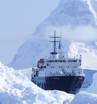 Oceanwide Expeditions: Ein Expeditionskreuzfahrtschiff fährt durch eisbedeckte Berge