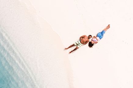 Kreta: Ein Paar liegt sich anschauend auf einem weißen Sandstrand